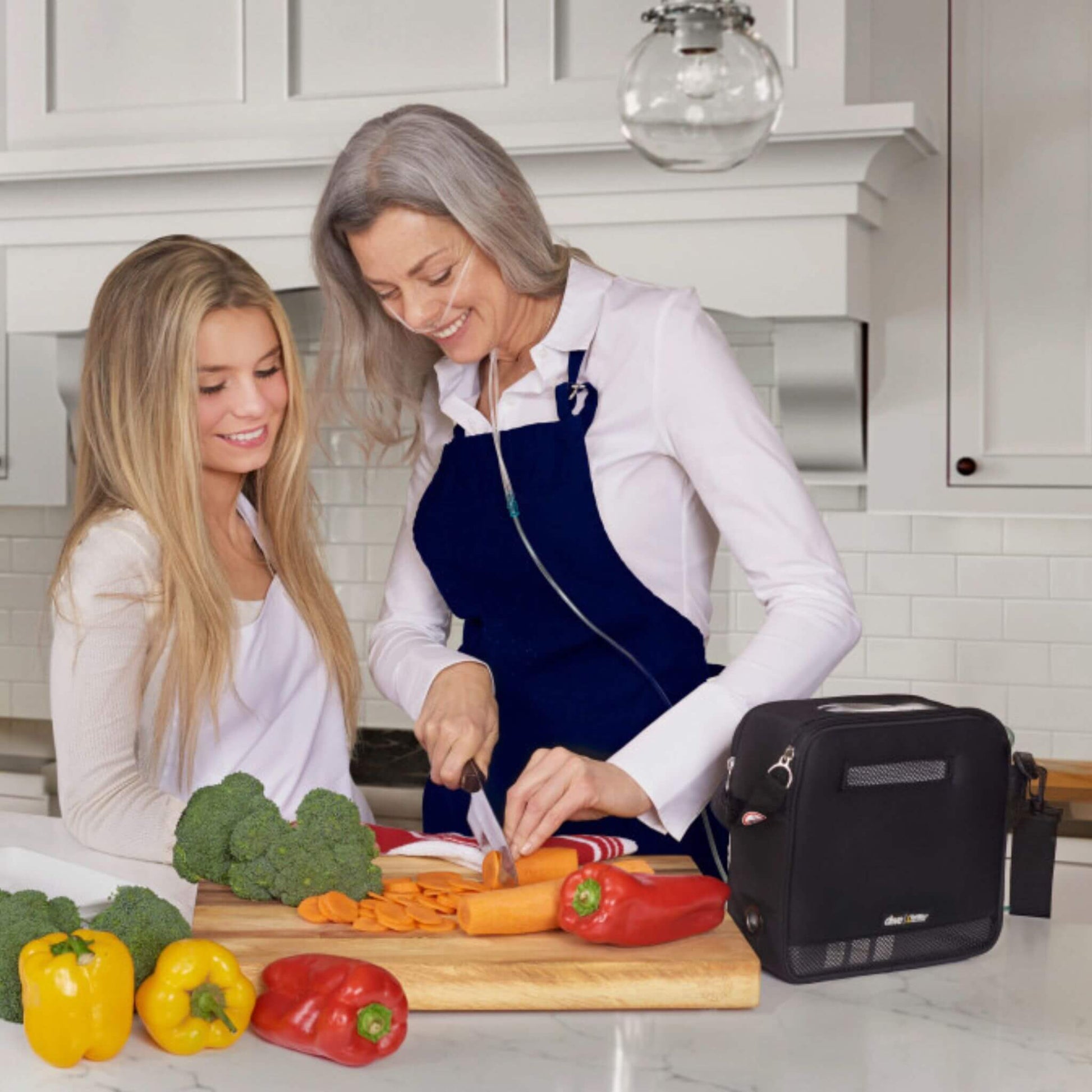 Lady cooking in the kitchen with Drive Devilbiss iGO2 Portable Oxygen Concentrator attached 