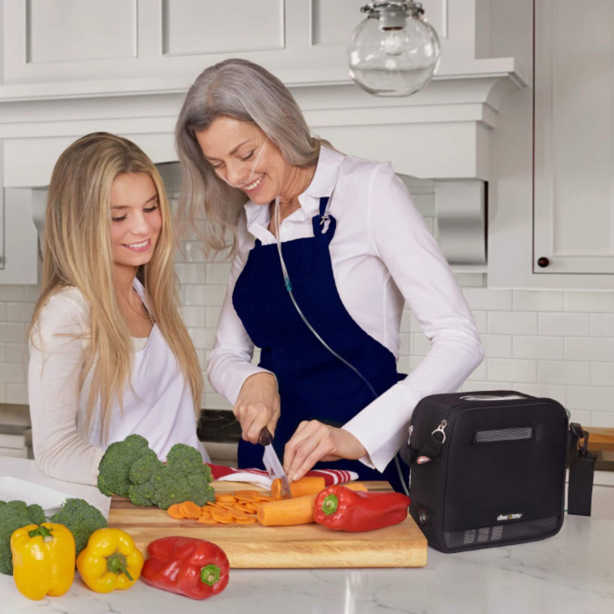 Lady cooking in the kitchen with Drive Devilbiss iGO2 Portable Oxygen Concentrator attached 