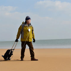 Person in yellow jacket with a portable oxygen concentrator on a sandy beach