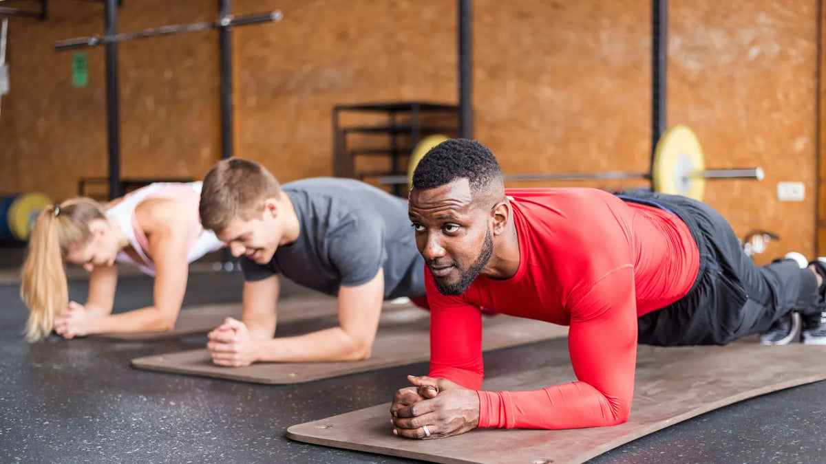 Three people holding a plank during a group workout in a gym